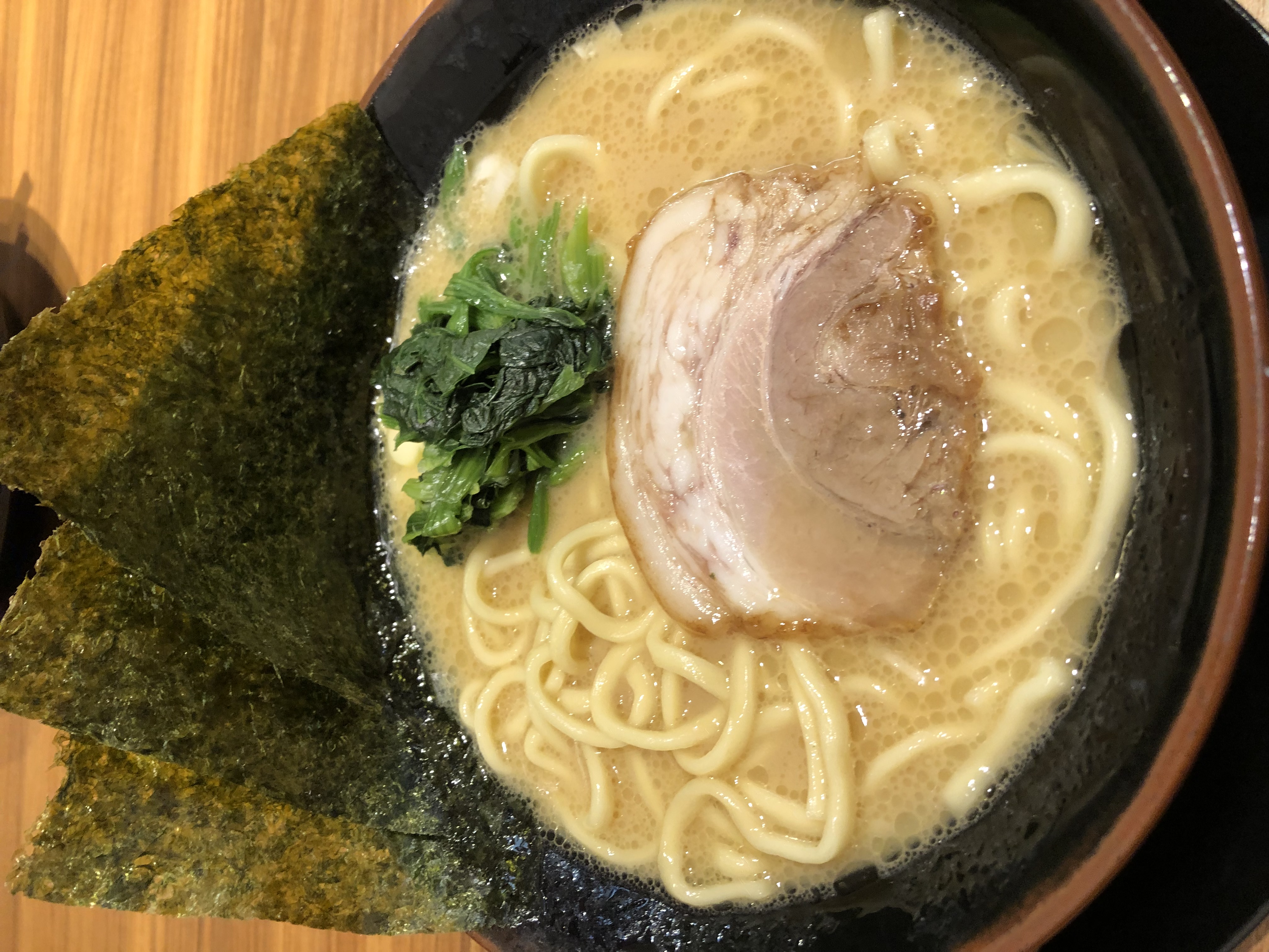 A bowl of tonkotsu ramen with milky white broth, thick noodles, chashu pork and nori